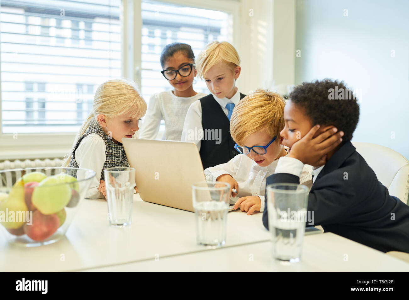 Groupe d'enfants en tant que développeur de logiciels équipe travaillant ensemble sur un ordinateur portable au bureau Banque D'Images
