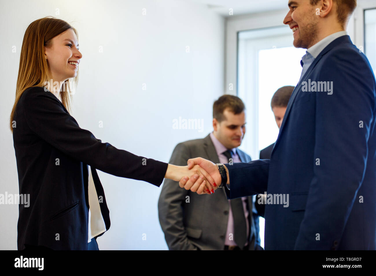 Jeune femme d'affaires et de l'homme portant une poignée de main foeground formelle vue. Banque D'Images