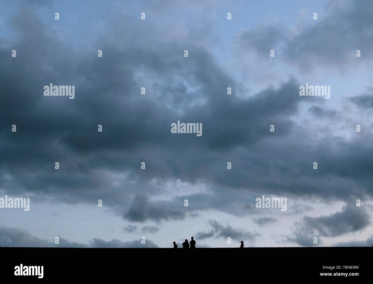 Silhouette de quatre personnes assis et levé par un mur, Espagne Banque D'Images
