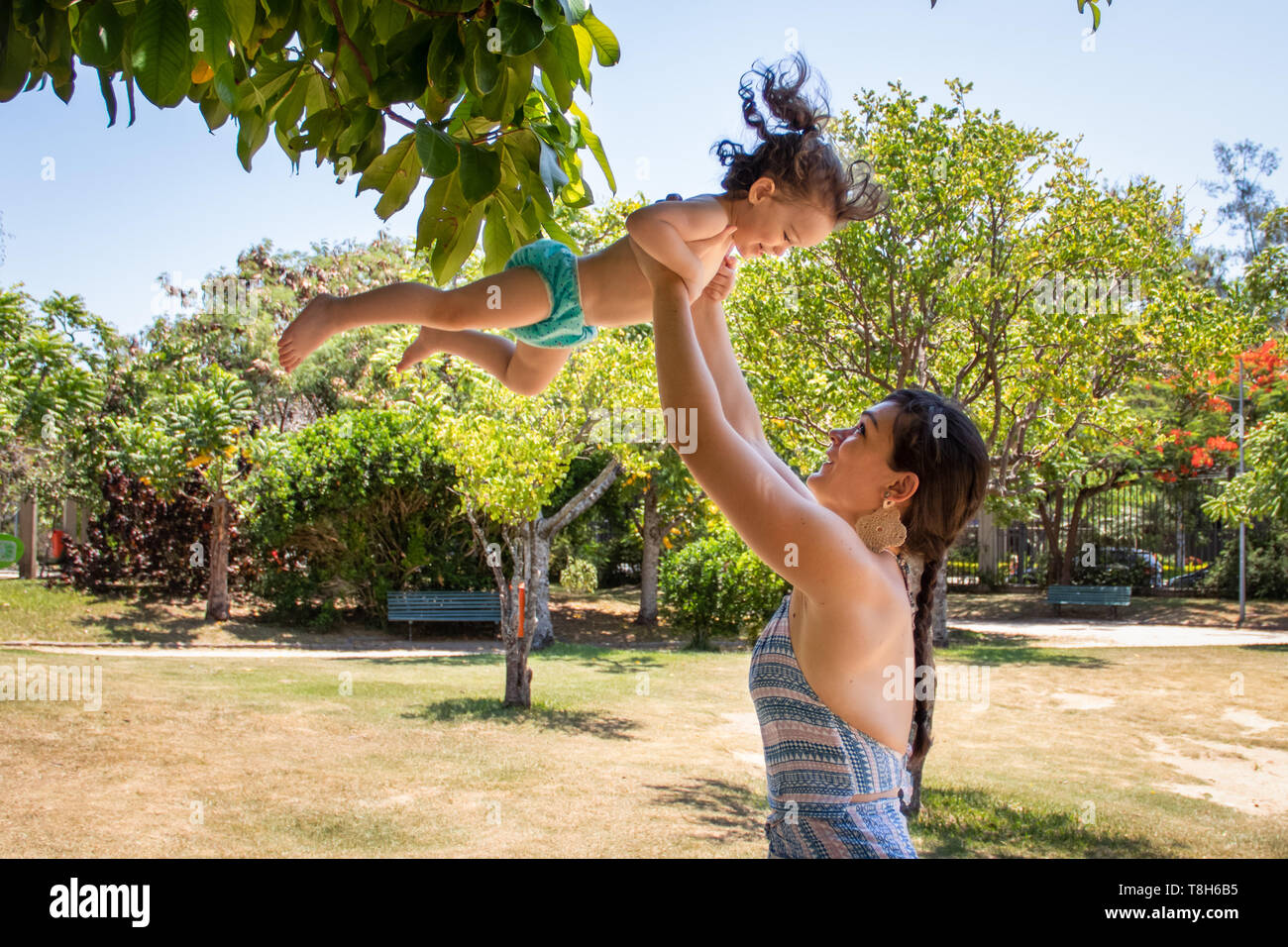 Femme debout dans le parc en sa fille dans l'air, Brésil Banque D'Images