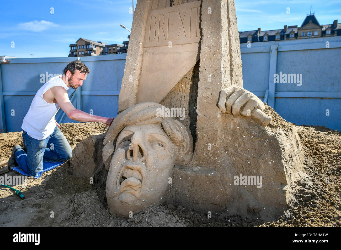 Artiste sculptures de sable Johannes Hogebrink travaille sur un Brexit sculpture à thème au Festival de sculptures de sable, Weston Weston-super-Mare, avec premier ministre Theresa peut réduire sa propre tête à l'aide d'une guillotine. Banque D'Images