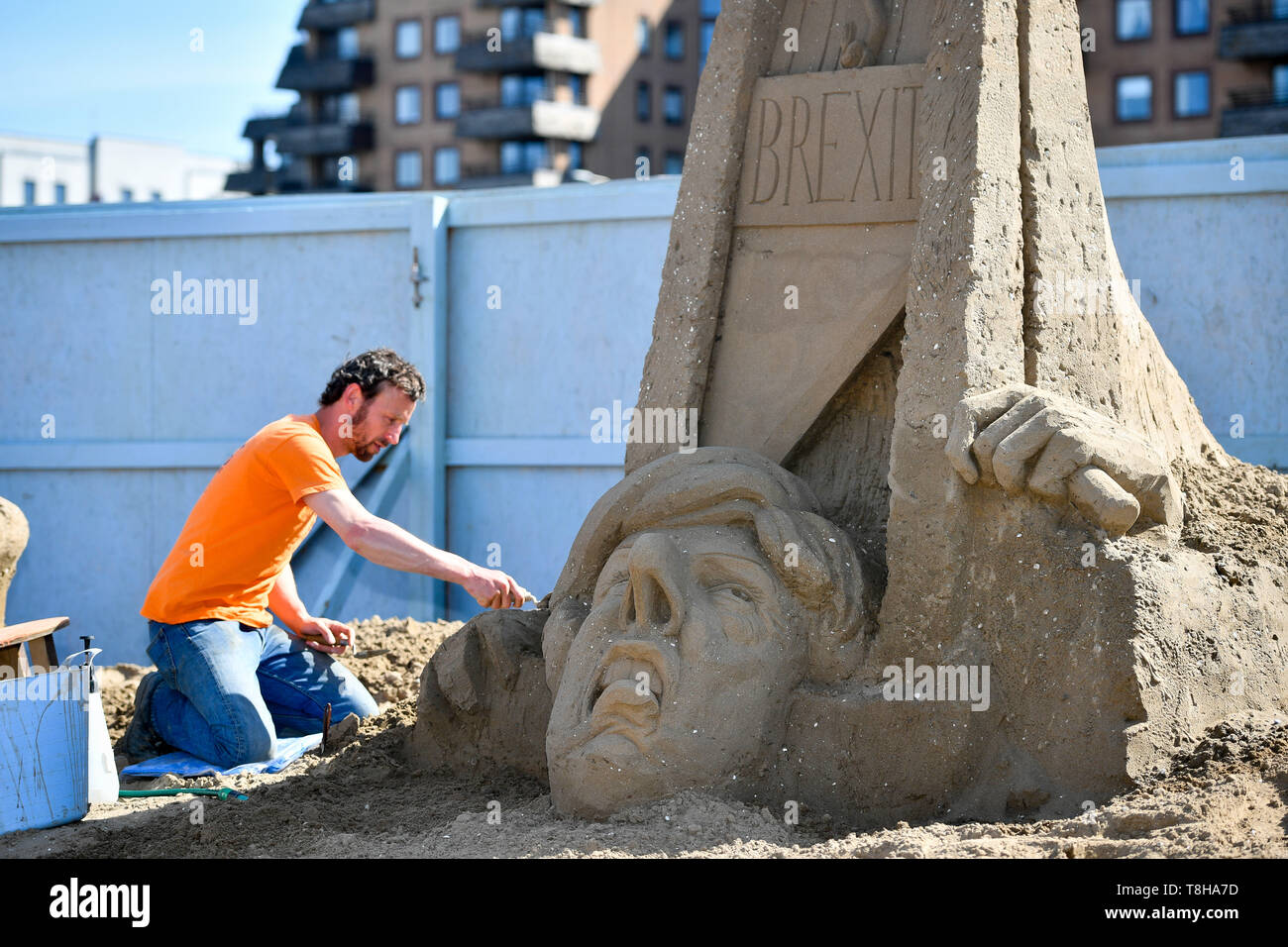 Artiste sculptures de sable Johannes Hogebrink travaille sur un Brexit sculpture à thème au Festival de sculptures de sable, Weston Weston-super-Mare, avec premier ministre Theresa peut réduire sa propre tête à l'aide d'une guillotine. Banque D'Images