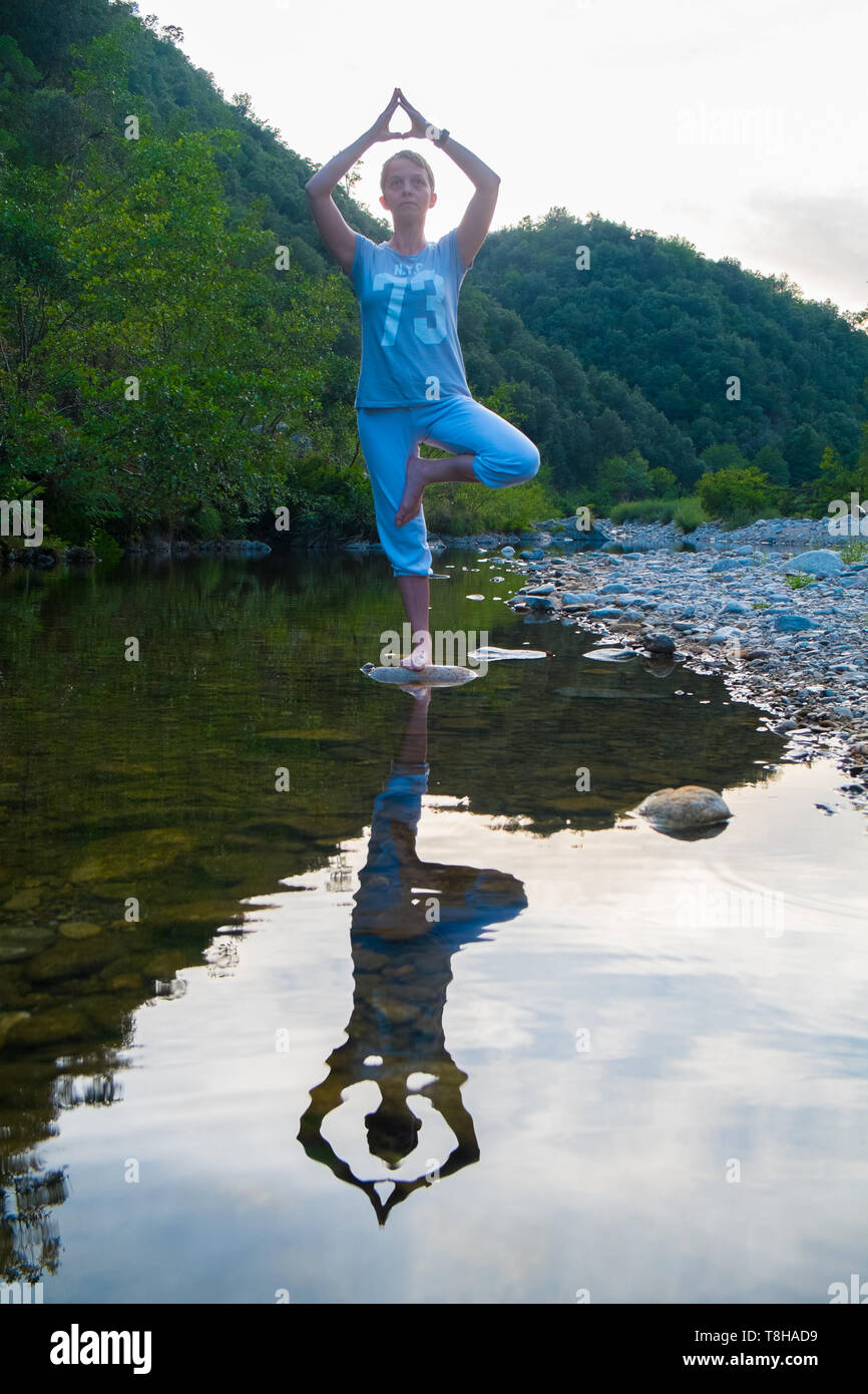Yoga sur un rocher dans une rivière de montagne Banque D'Images