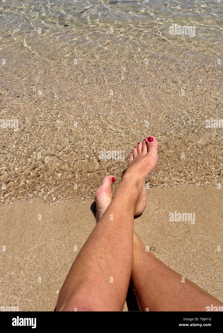 Close-up of a woman's les jambes croisées à la cheville sur la plage, à Malte Banque D'Images