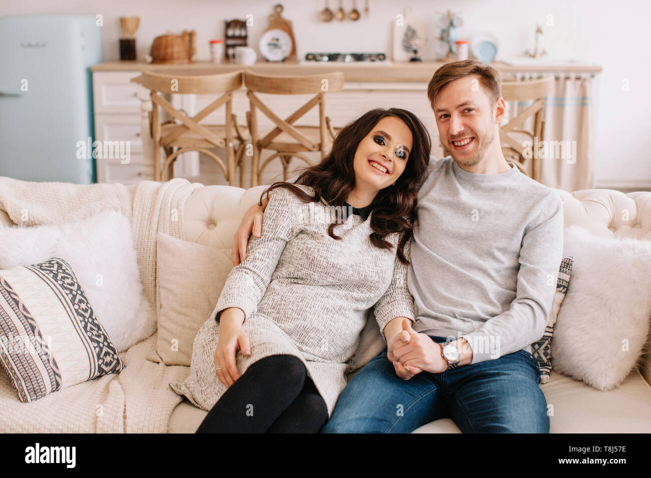 Heureux couple sitting on a couch holding hands Banque D'Images