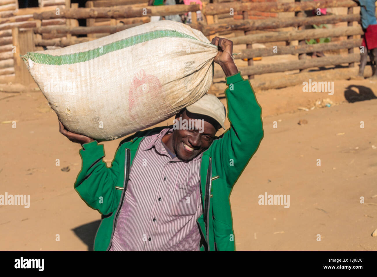 Malawian homme portant un sac de farine de maïs sur ses épaules après broyage dans un village de Malawi Banque D'Images