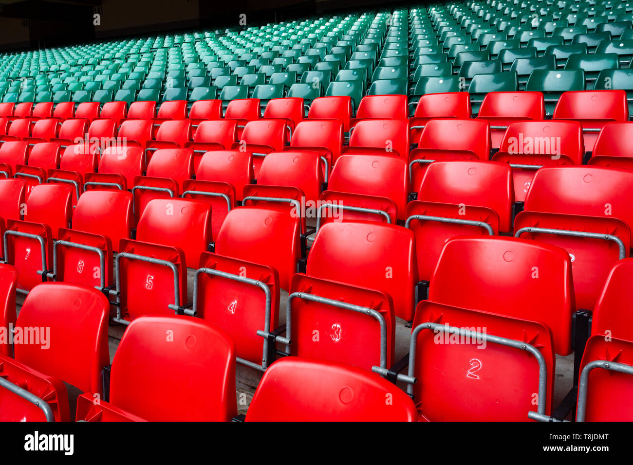 Des sièges en plastique rouge et vert dans un grand stade vide, Banque D'Images