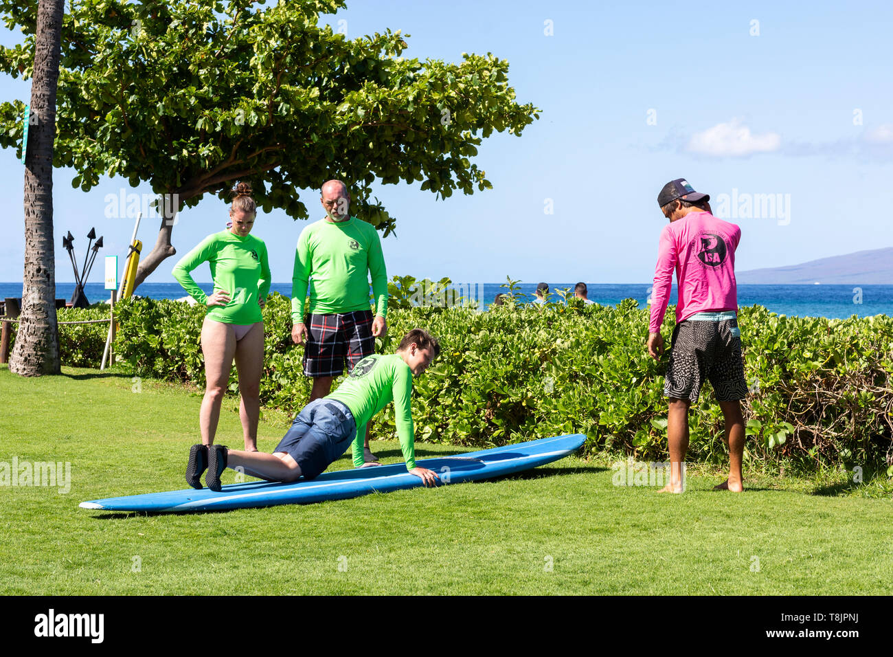 Une mère et un père regardent alors que leur fils prend une leçon de surf d'un pro local à Hawaï, Etats-Unis. Banque D'Images