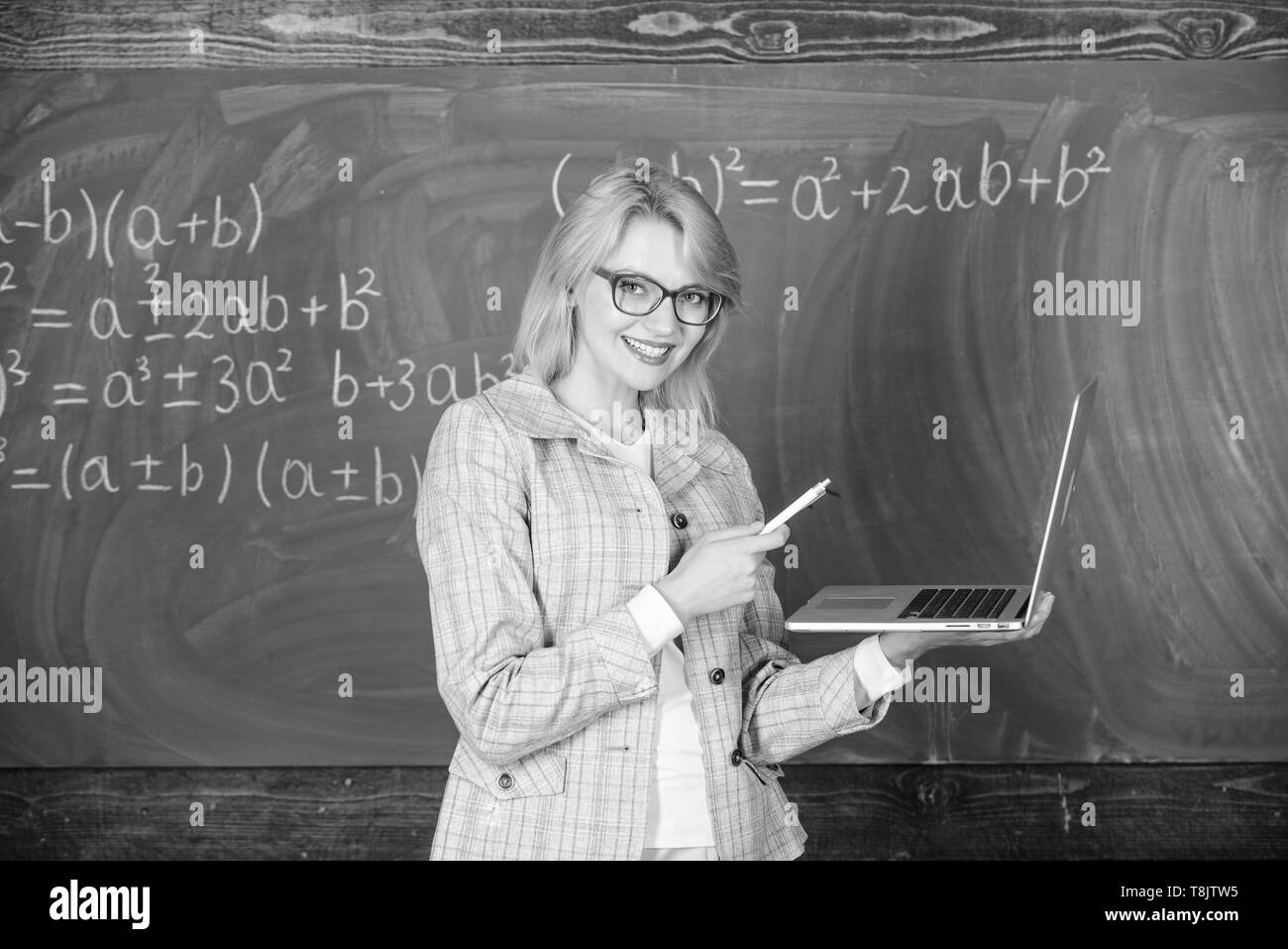 Smart éducateur dame avec ordinateur portable moderne tableau internet surf arrière-plan. L'éducation scolaire de base. Enseignante portent des lunettes est titulaire d'ordinateur portable Internet surf. Les technologies numériques concept. Banque D'Images