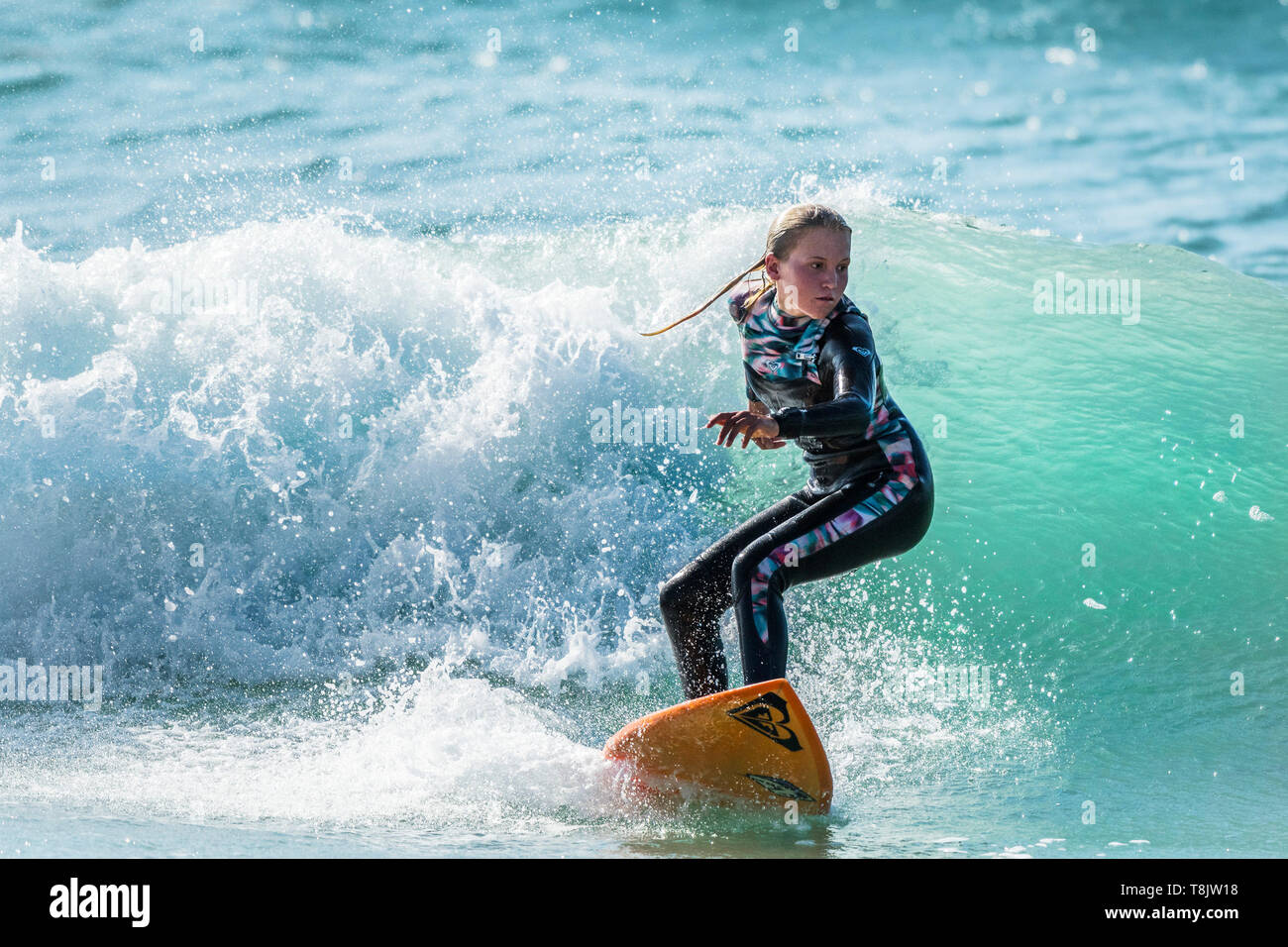 Surf spectaculaire action comme une jeune femme monte un vague à surfer dans Fistral Newquay en Cornouailles. Banque D'Images