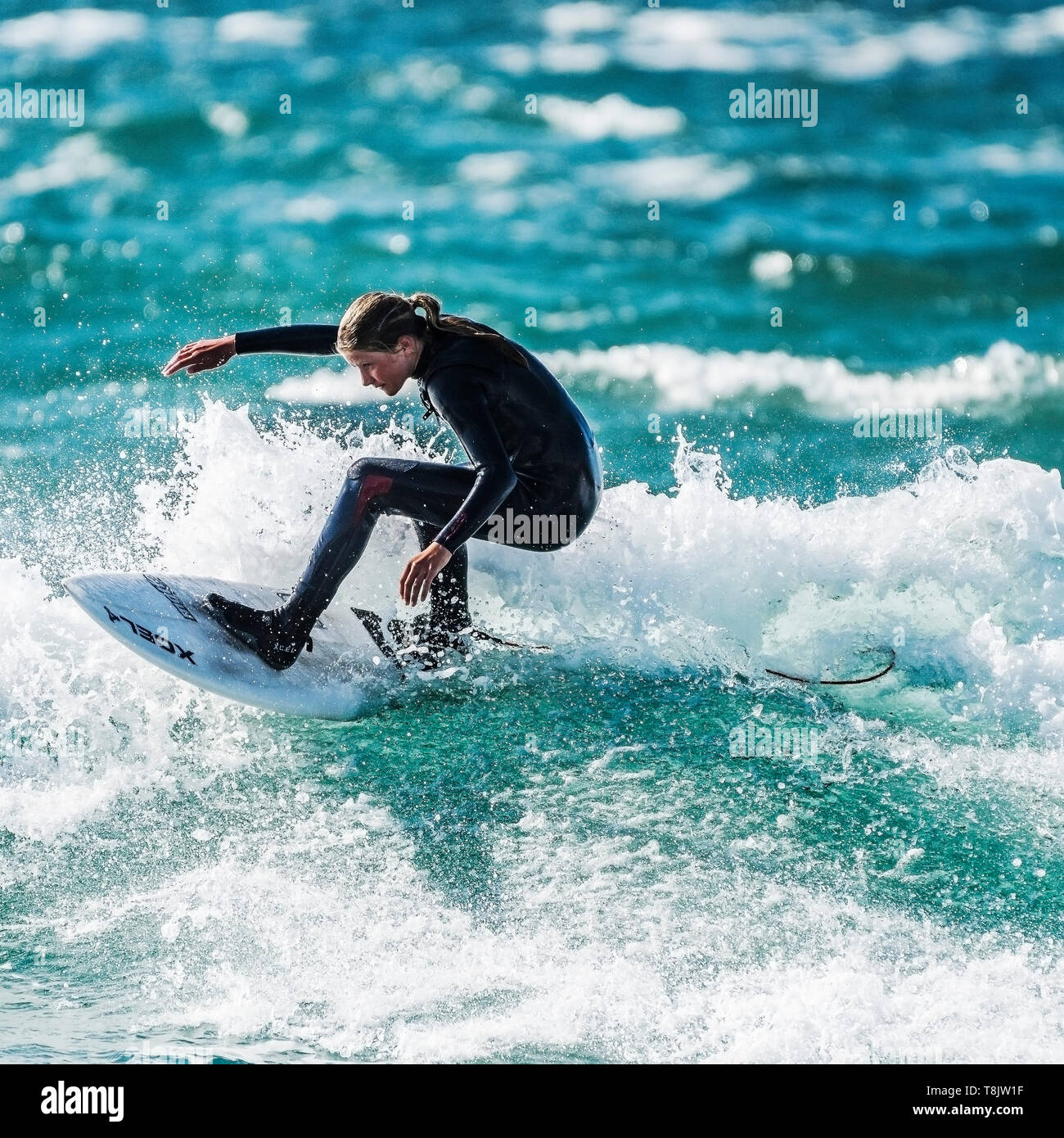 Action de surf comme une jeune adolescente manèges surfer une vague à Newquay dans Fistral à Cornwall. Banque D'Images