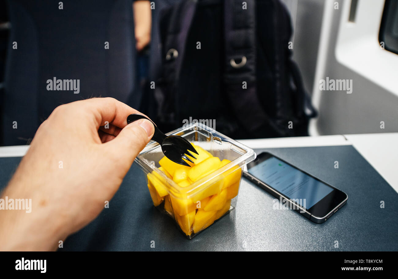 L'homme en train de manger avec la fourchette à salade de pastèque - voyage en train jusqu'au petit smartphone sur la table Banque D'Images