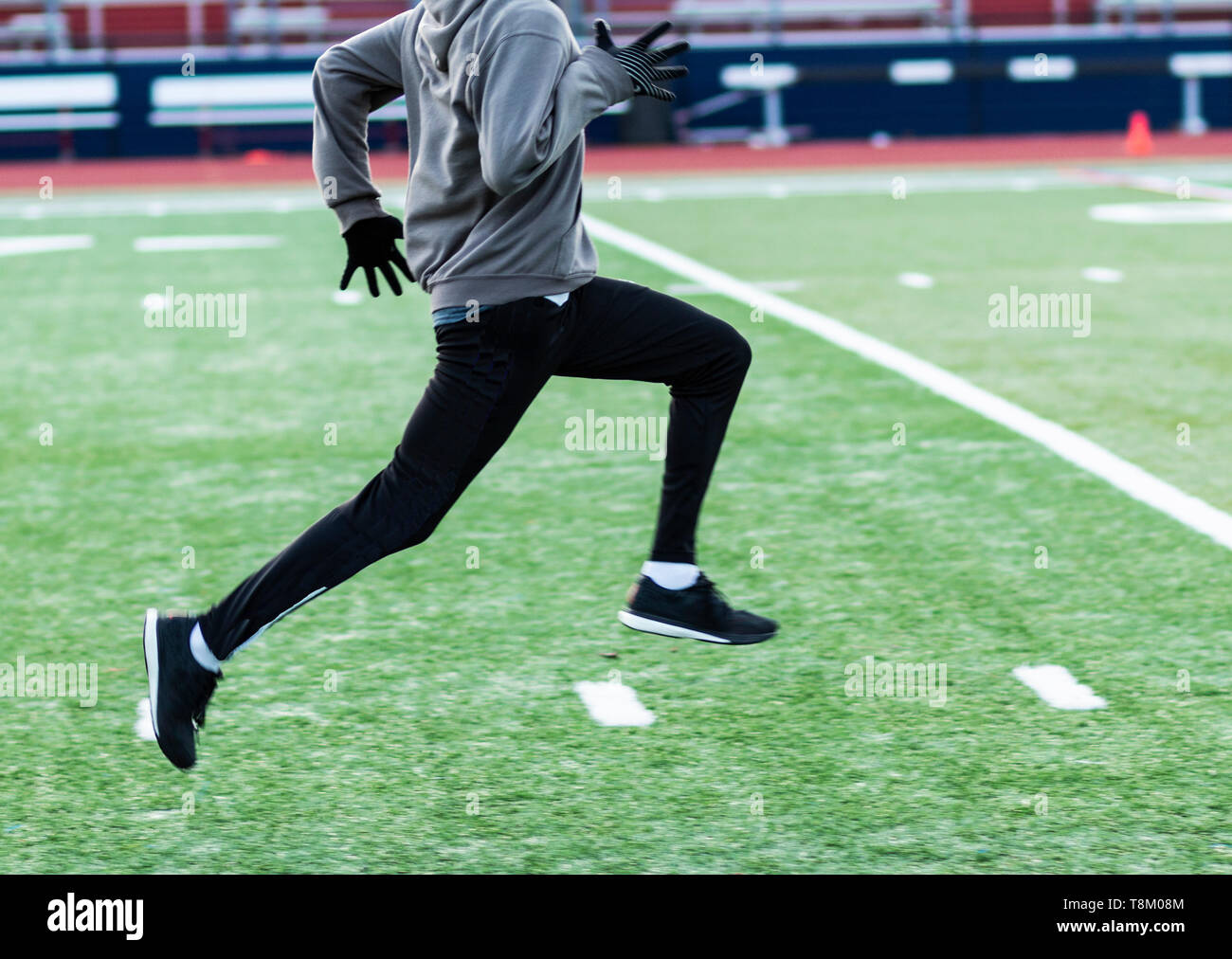 Une école est sprinter courir vite sur un champ de gazon vert en hiver la voie et la pratique sur le terrain. Banque D'Images