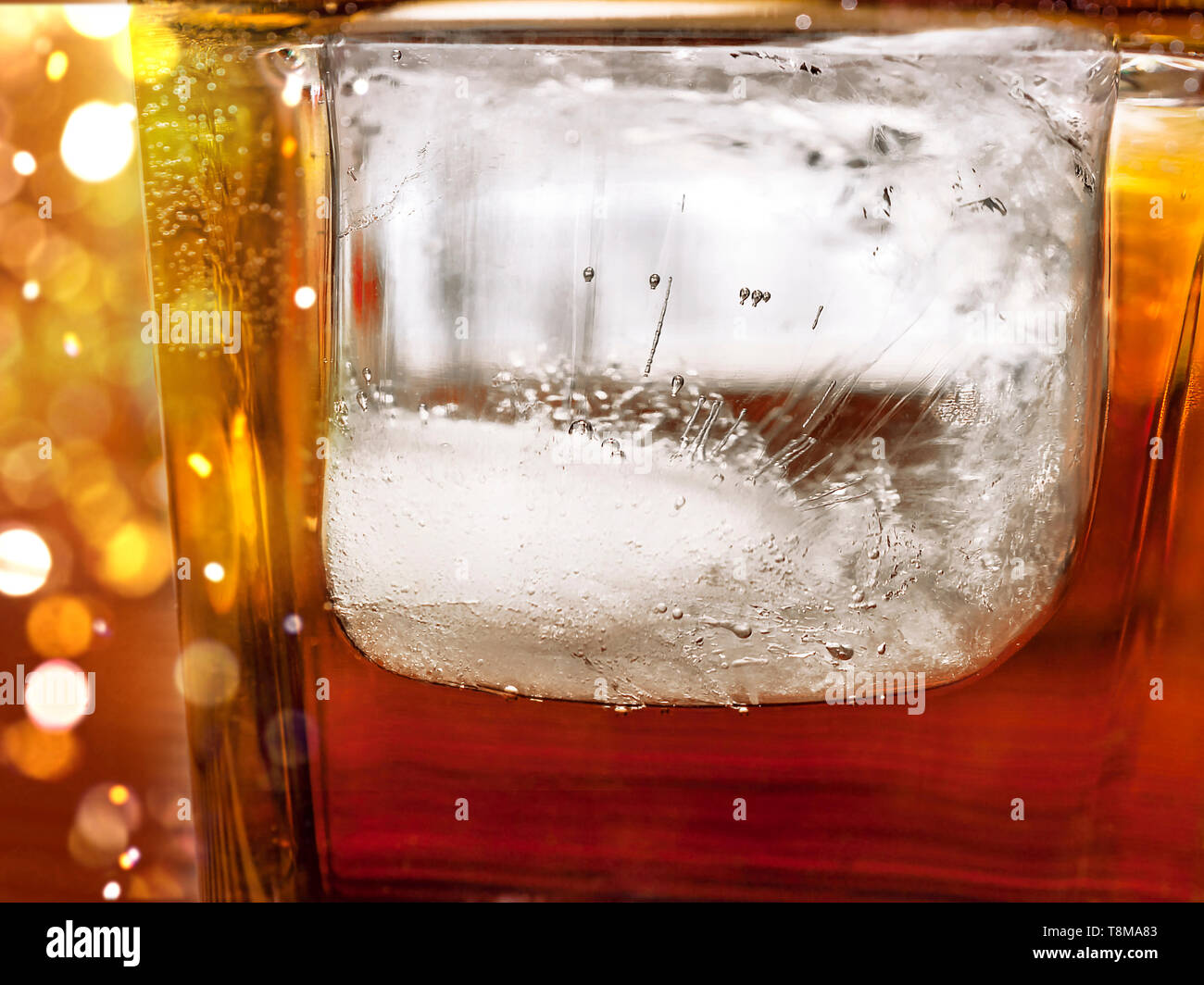 Gros glaçon dans un verre de whisky et un verre de coke. Détails de Texture de la glace. Feux de célébration. Banque D'Images