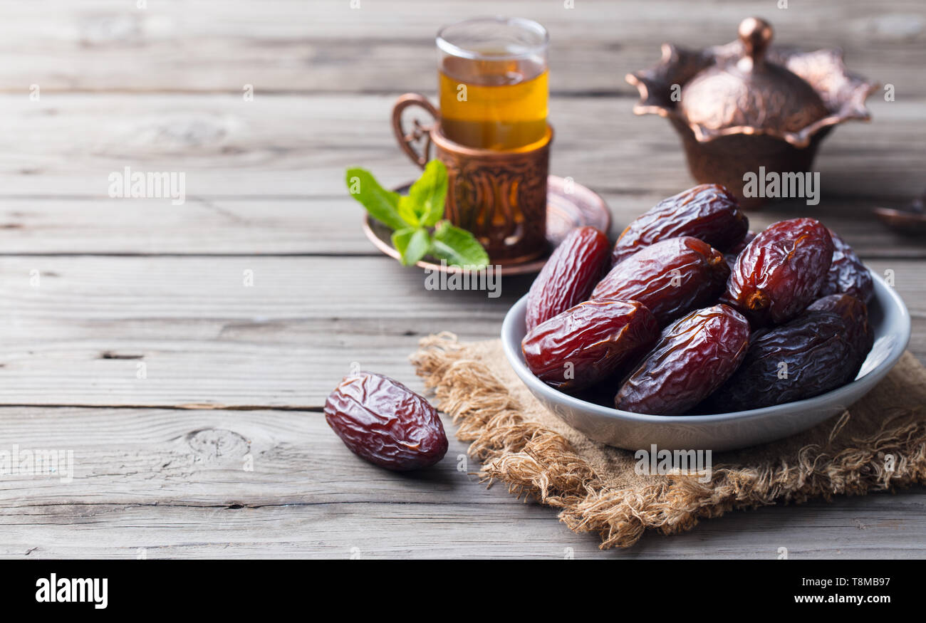 Medjool Dates dans un bol avec du thé. Ramadan kareem. Fond de bois gris. Copier l'espace. Banque D'Images