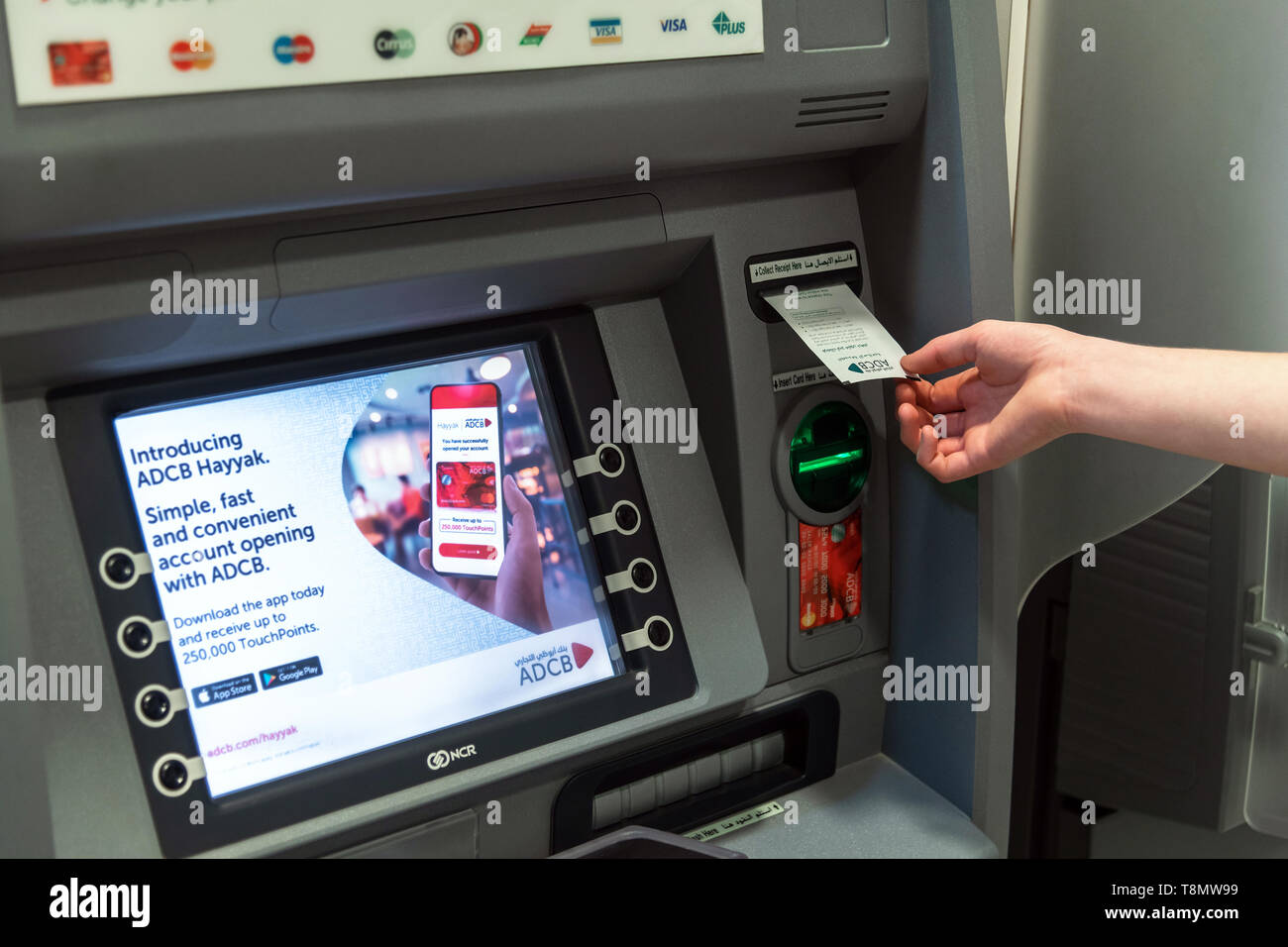 Abu Dhabi, UAE - 29 mars. 2019. La main d'un homme saisit le papier vérifier dans un distributeur d'Abu Dhabi Commercial Bank Banque D'Images