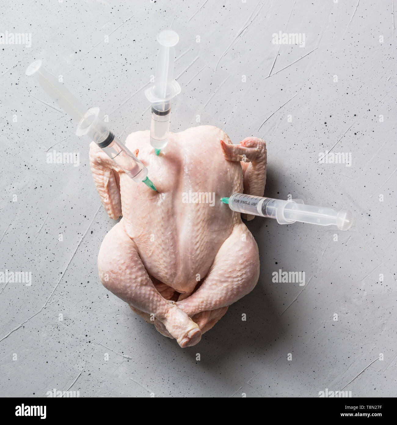 Le poulet frais avec des seringues bloqué sur fond de béton. Vue de dessus. Banque D'Images