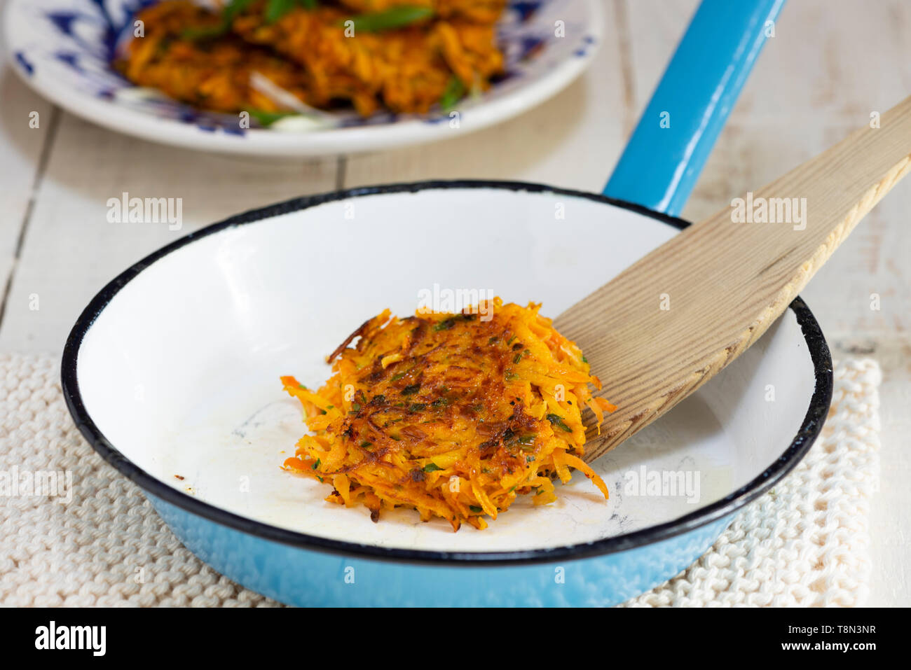 Rosti de pommes de terre et la carotte dans une poêle en émail bleu. Banque D'Images