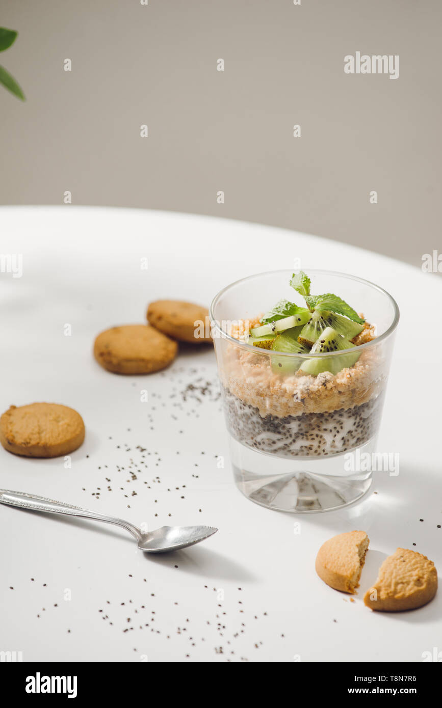 Prêt à manger sain un petit déjeuner nutritif - Granola aux amandes, graines de chia, banane et kiwi fruits et de baies et d'un bocal avec du lait à proximité Banque D'Images