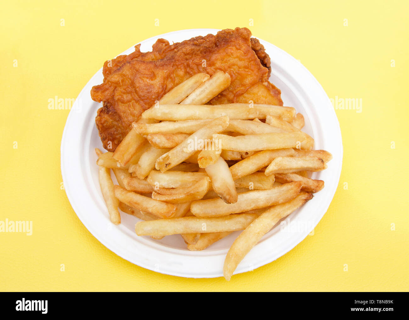 Livre blanc la plaque avec du poisson et des frites sur nappe jaune. Foire de rue populaire de la nourriture. Banque D'Images