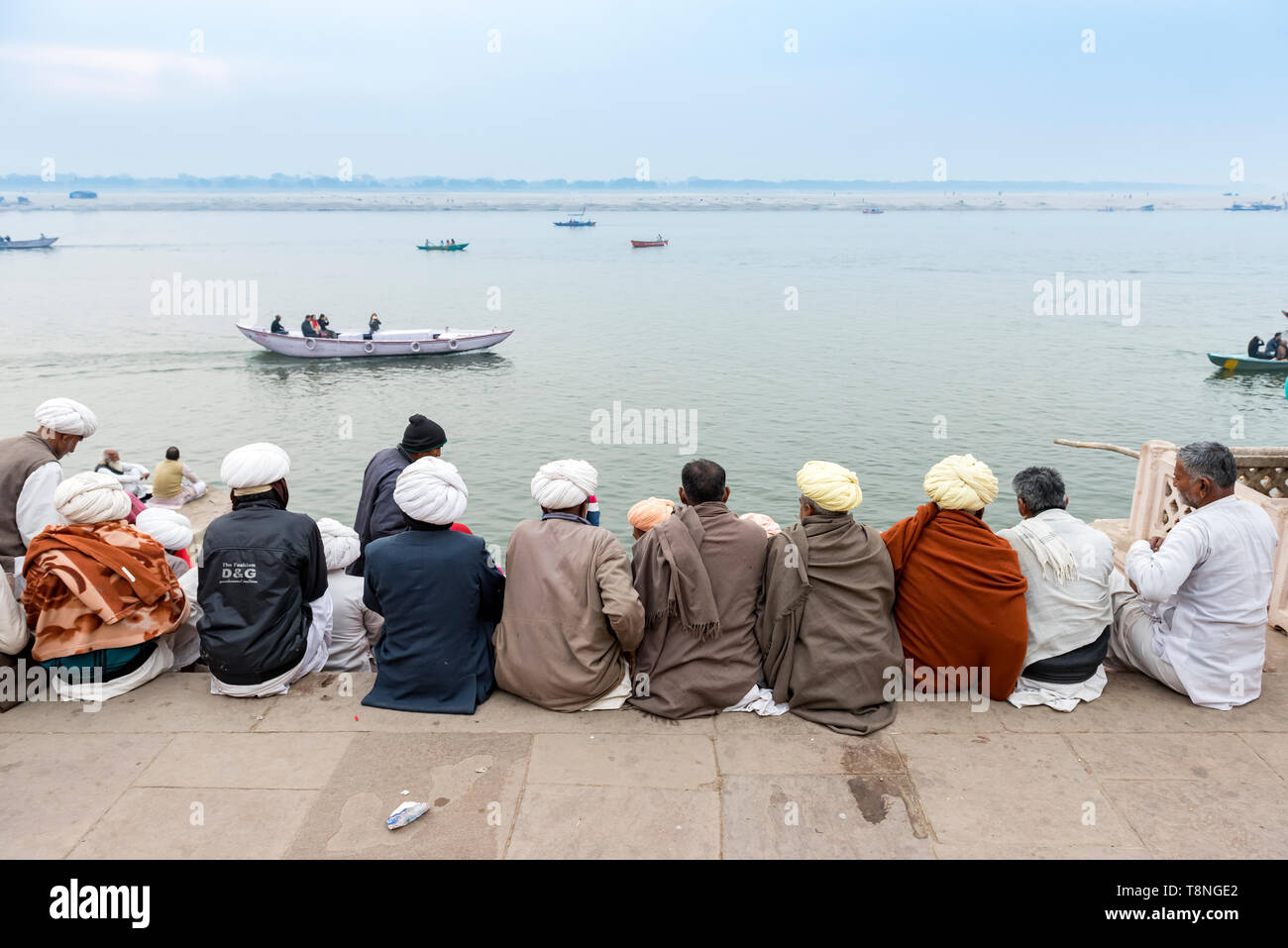 Groupe d'hommes Indiens s'asseoir sur les ghats et regarder Gange, Varanasi, Inde Banque D'Images