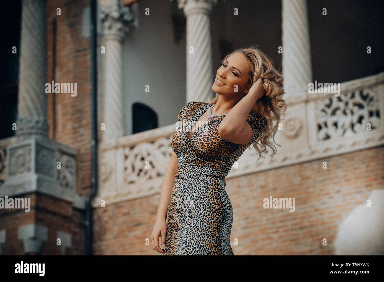 Elegant blonde woman posing contre un mur portant une robe imprimé animal. Banque D'Images