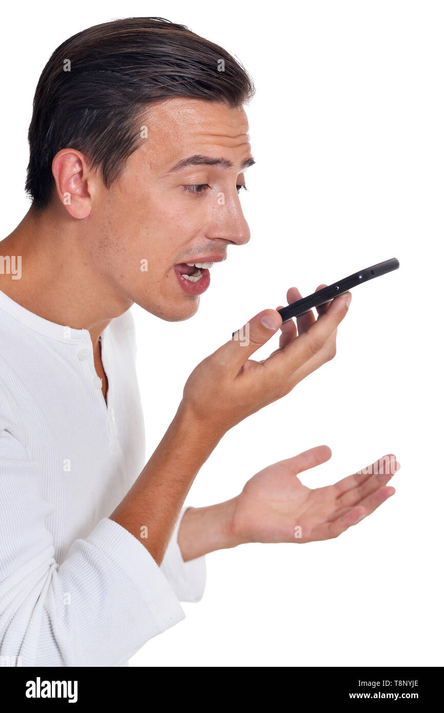 Portrait de jeune homme en colère dans les vêtements blancs de crier sur smartphone posant sur fond blanc Banque D'Images