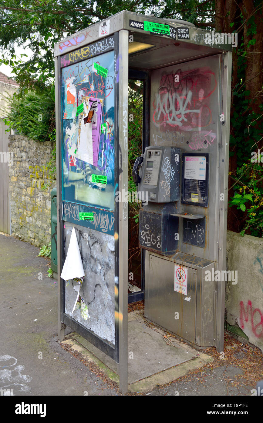 Téléphone britannique moderne fort vandalisé avec des affiches, marquage et graffiti Banque D'Images