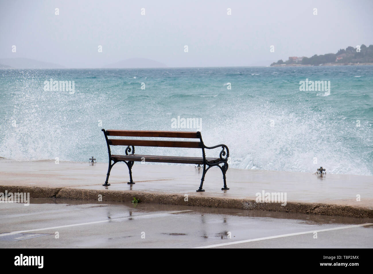 Banc vide par la mer agitée éclaboussé par la vague en Dalmatie ville balnéaire en hors saison pendant une forte pluie et vent du sud Banque D'Images