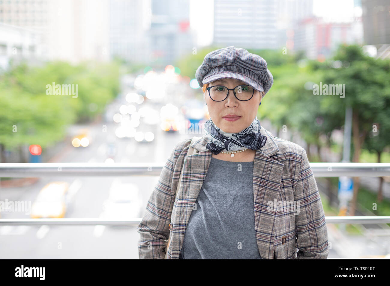 Taiwanais à la mode femme d'origine chinoise appuyé contre balustrade avec ville en arrière-plan Banque D'Images