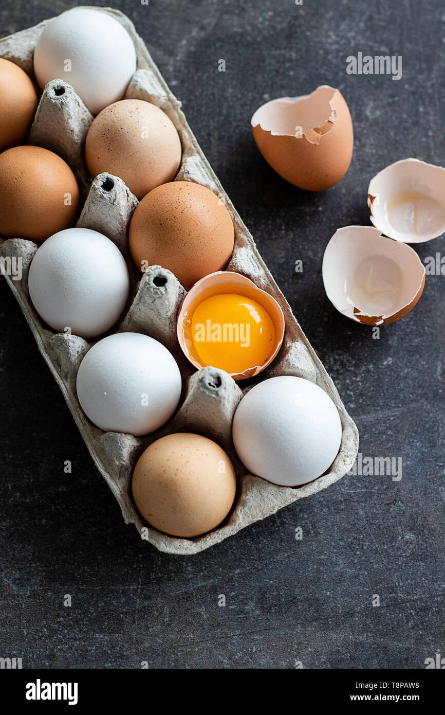 Les œufs crus biologiques frais, blanc, beige et brun, l'un est fissuré Banque D'Images