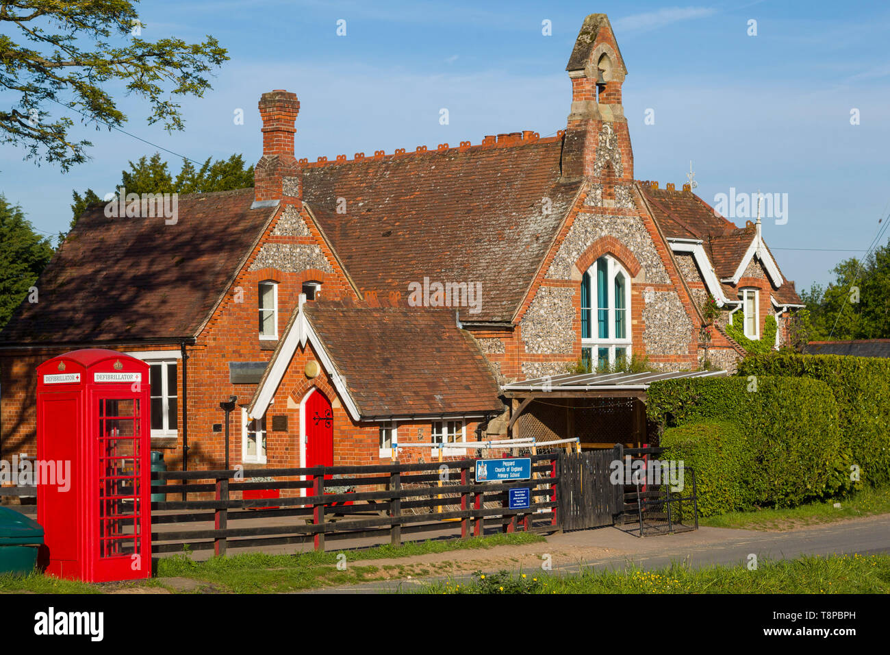 Victorien traditionnel briques et silex bâtiment scolaire, toujours utilisé à Peppard, Oxfordshire avec un téléphone rouge fort converti pour un défibrillateur Banque D'Images