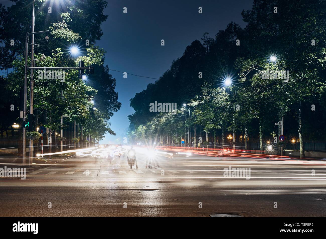 Les motos en attente sur carrefour. Les sentiers de la lumière de la circulation en ville. Nuit à Hanoi, Vietnam. Banque D'Images