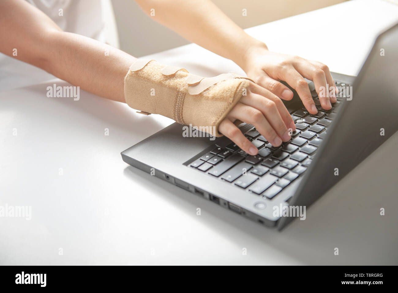 La douleur au poignet à l'aide de l'ordinateur de bureau, par contre le syndrome de la douleur ou une blessure, utiliser femme bandage élastique à traiter. Banque D'Images