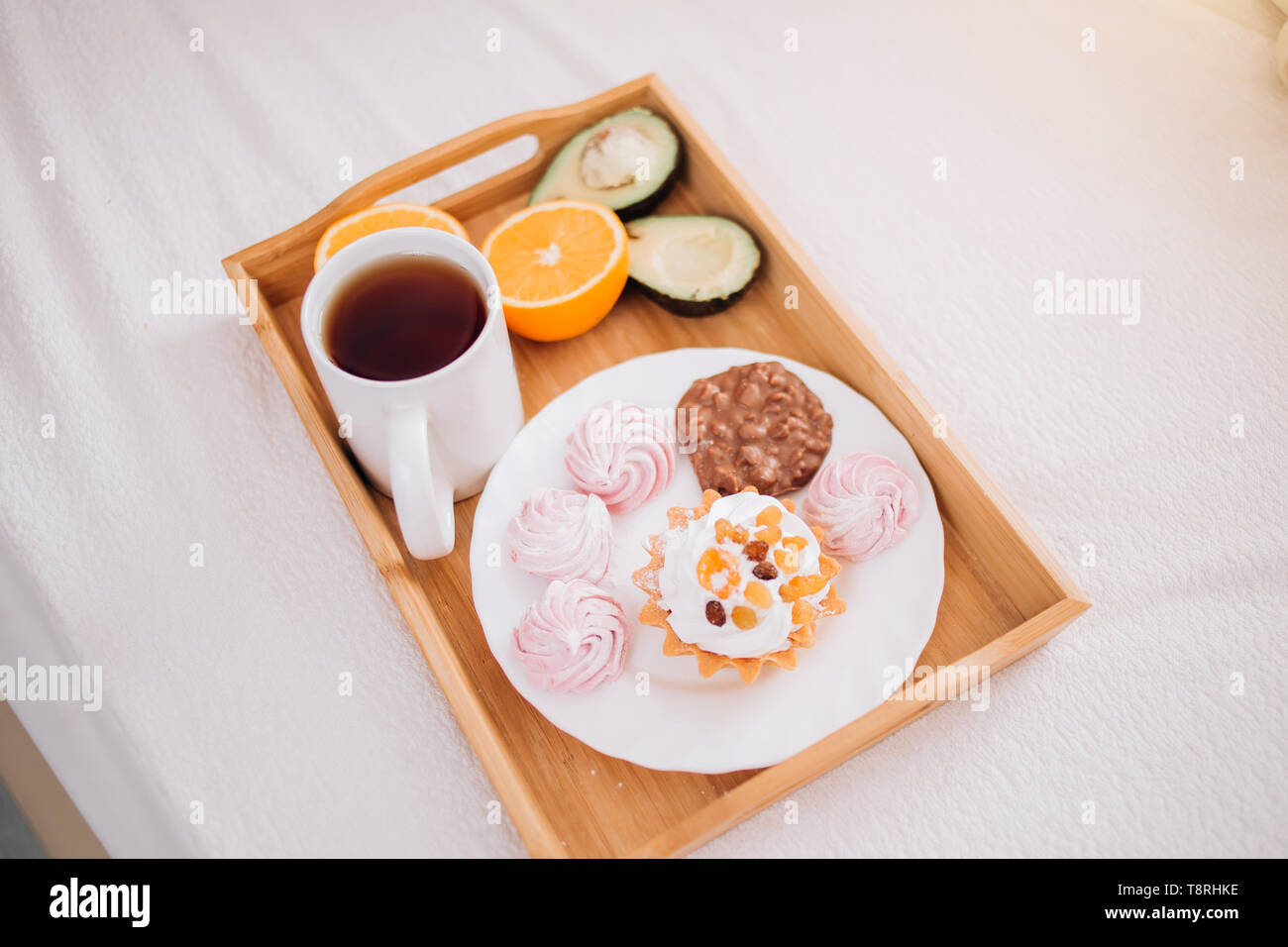 Bon matin petit déjeuner au lit avec un plateau, orange, l'avocat, gâteau, guimauves, biscuits au chocolat en barre en bois de vie, nourriture, repas, un confort d'accueil Banque D'Images