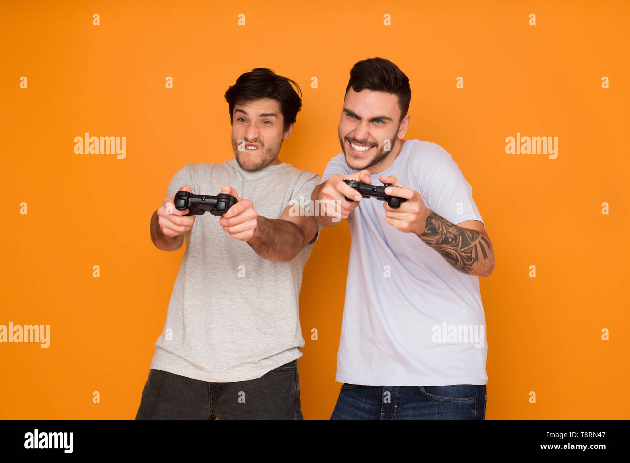 Deux amis à jouer aux jeux vidéo sur fond orange Banque D'Images