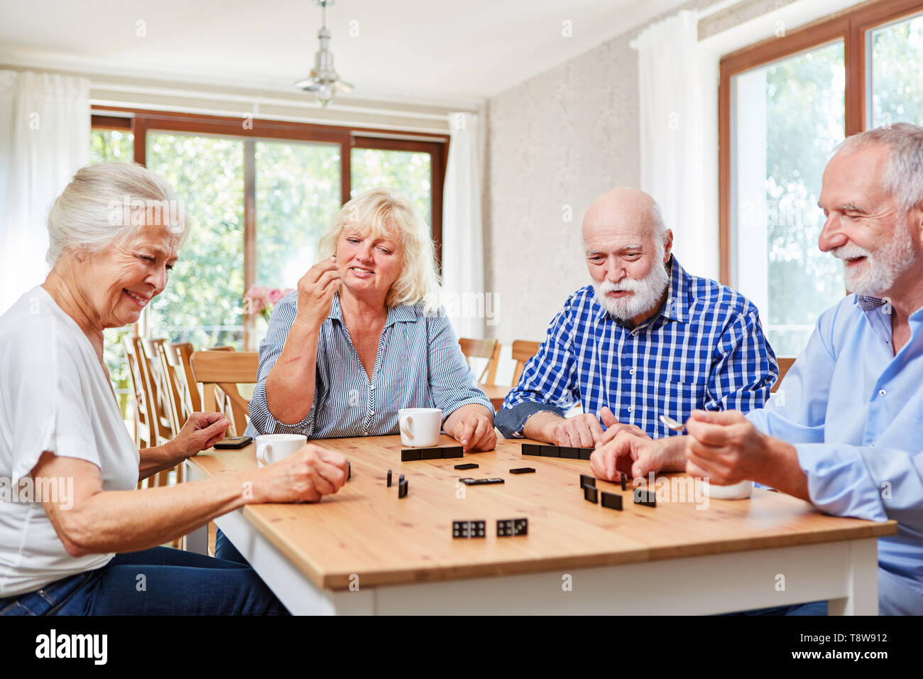 Groupe d'aînés jouer aux dominos que l'emploi dans maison de retraite Banque D'Images