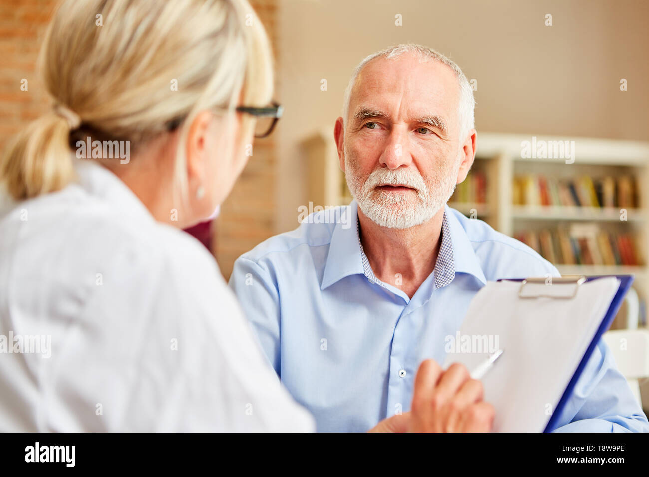 Senior patient écoute attentivement son médecin lors de la consultation Banque D'Images