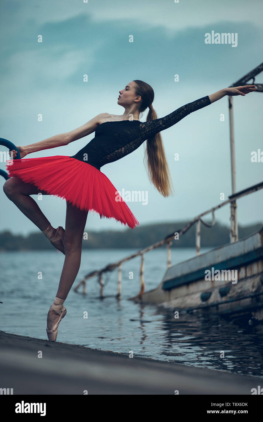 Ballerine danse sur la côte du fleuve dans un tutu rouge et noir contre  l'arrière-plan de vieux bateau Photo Stock - Alamy