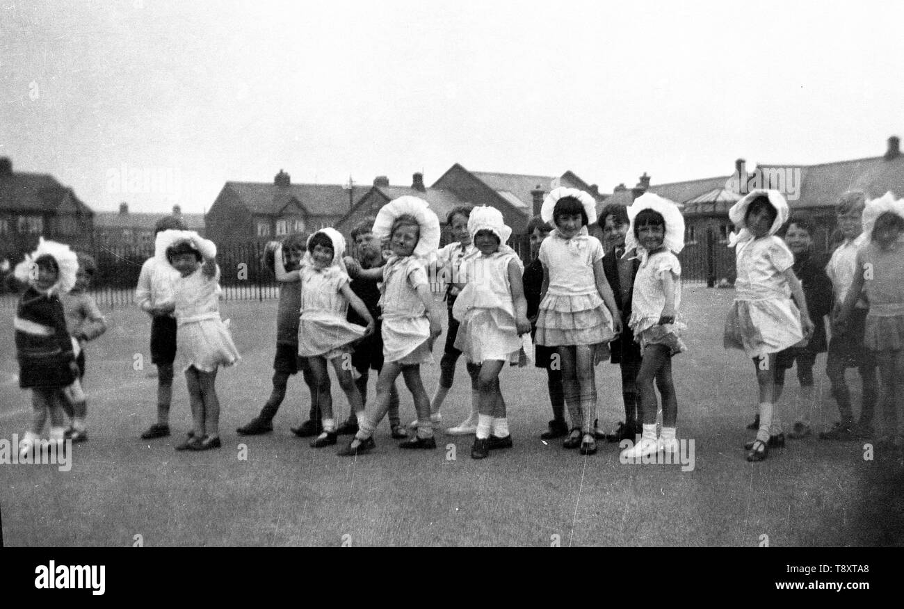 Heureux les enfants espiègles dans Fancy Dress - habillés comme des nourrissons en bonnets - à l'école. c1935. Photo par Tony Henshaw Banque D'Images