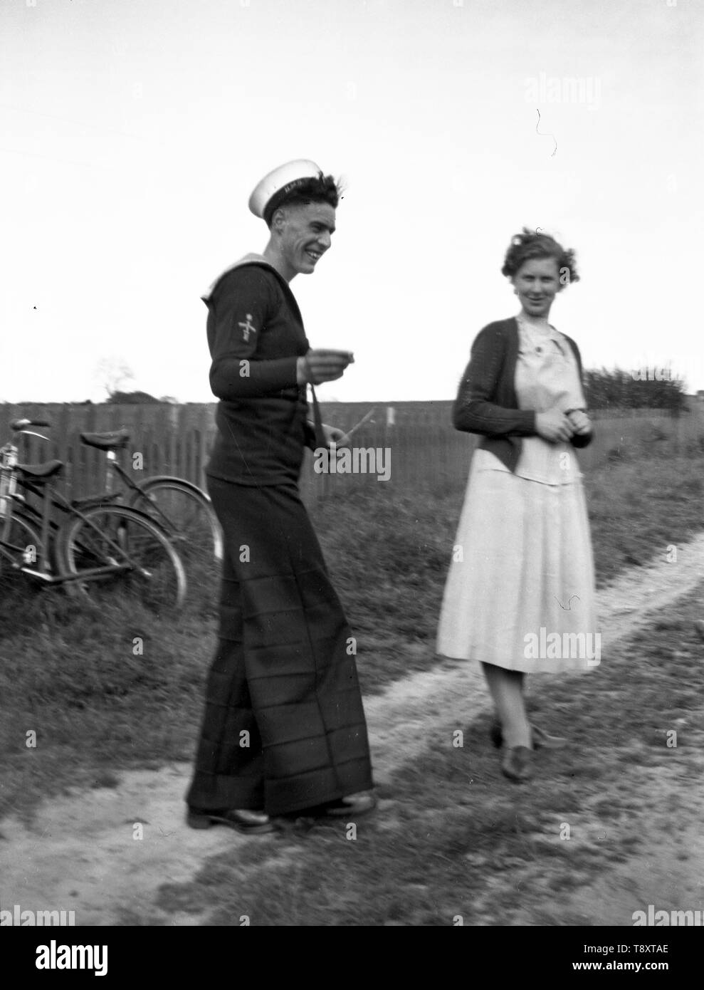 Une franchise de droit d'un marin britannique en uniforme en congé avec une femme. Remarque Le pantalon bas. c1930 Photo de Tony Henshaw Banque D'Images