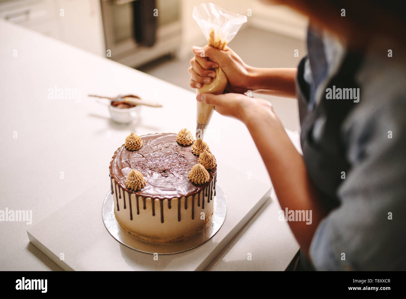 Close up of a woman decorating cake au chocolat dans la cuisine. Femme chef decorating cake avec de la crème fouettée à l'aide de la technique de la tuyauterie. Banque D'Images