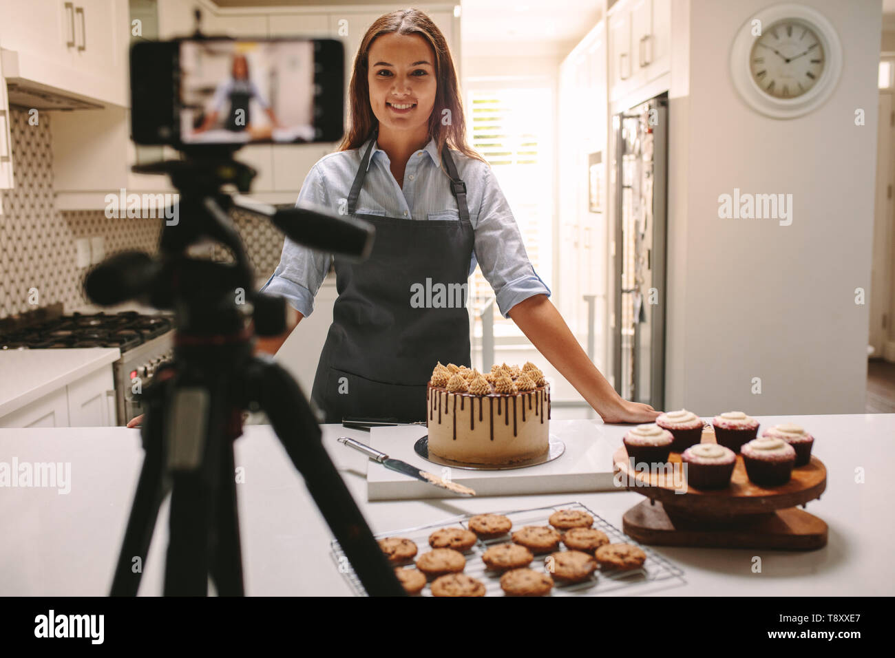 Femme de l'enregistrement vidéo dans sa cuisine. Chef pâtissier de créer un contenu vidéo blog. Banque D'Images