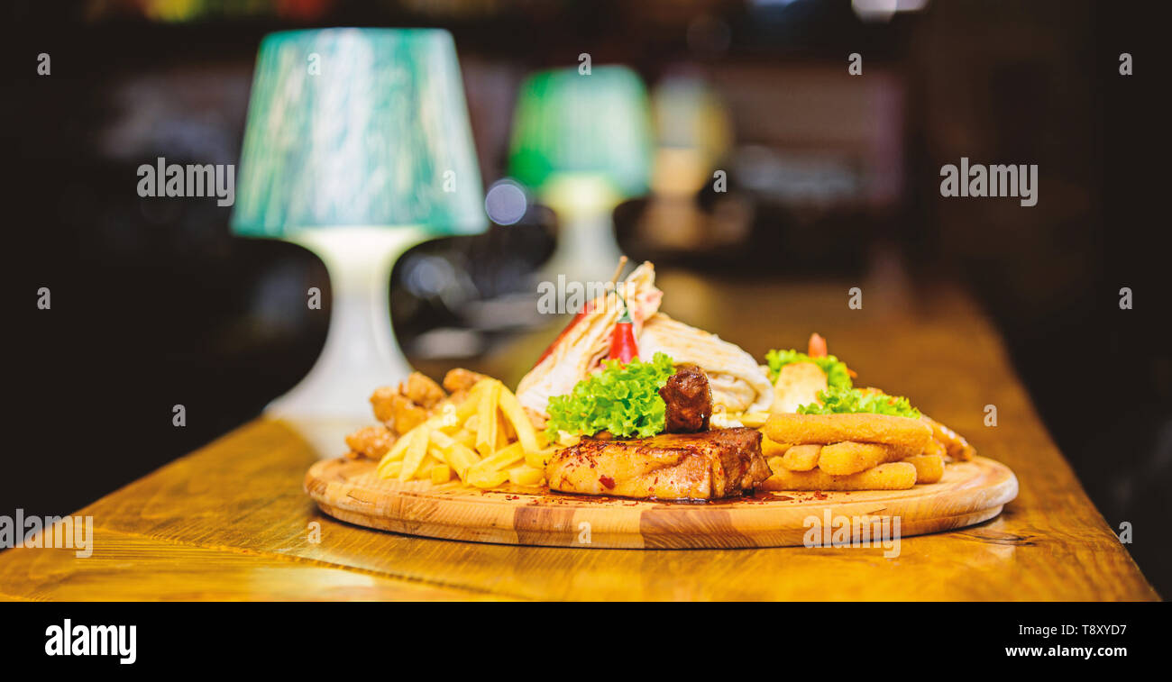 Menu snack-bar. Calories élevé pour le groupe d'amis. De délicieux en-cas savoureux. Snack pour la bière. Les repas au restaurant. Planche de bois avec beaucoup de frites et bâtonnets de poisson viande burrito steak servi avec une salade. Banque D'Images