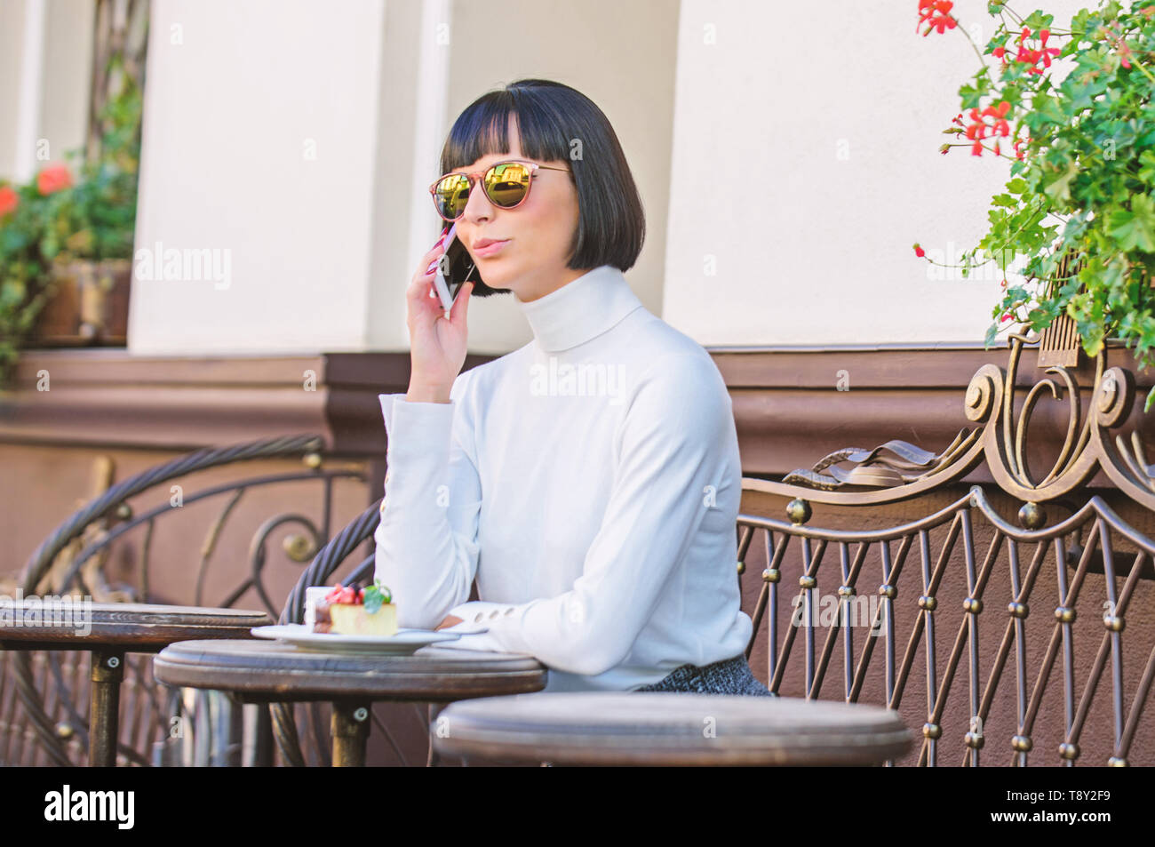 Appelez un ami. Mode Fille dame avec smartphone. Concept de loisirs. Femme jolie brune élégante loisirs dépenser café terrasse arrière-plan. Agréable moment et les loisirs. Se détendre et pause café. Banque D'Images