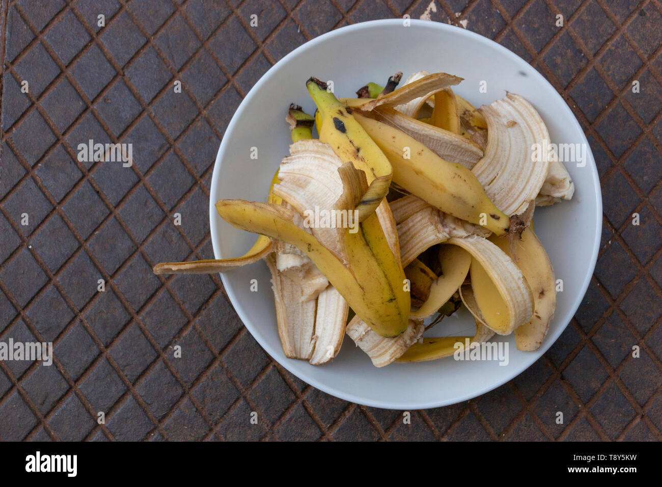 Une vue en gros plan d'une plaque ronde blanche avec éclats bananna empilées en elle assis sur un couvercle de métal Banque D'Images