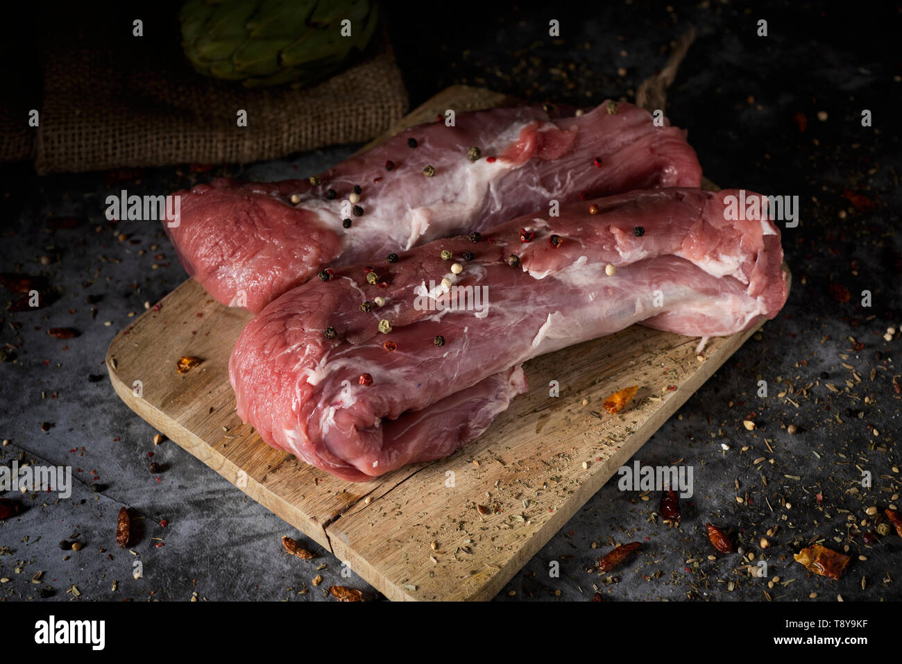 Libre de quelques morceaux de filet de porc cru, sur une planche à découper en bois, placé sur une table ou un comptoir rustique Banque D'Images