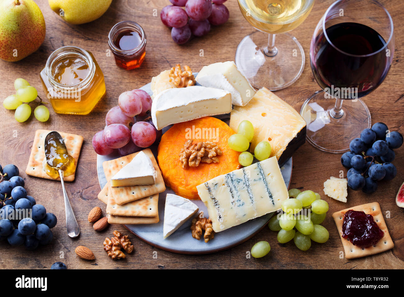 Assortiment de fromages, raisins à vin rouge et blanc dans les verres. Fond de bois. Vue d'en haut. Banque D'Images