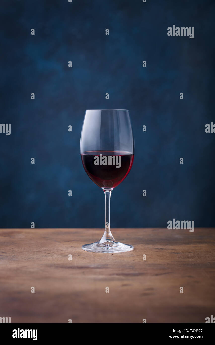 Verre de vin rouge sur la table en bois. Fond bleu. Copier l'espace. Banque D'Images