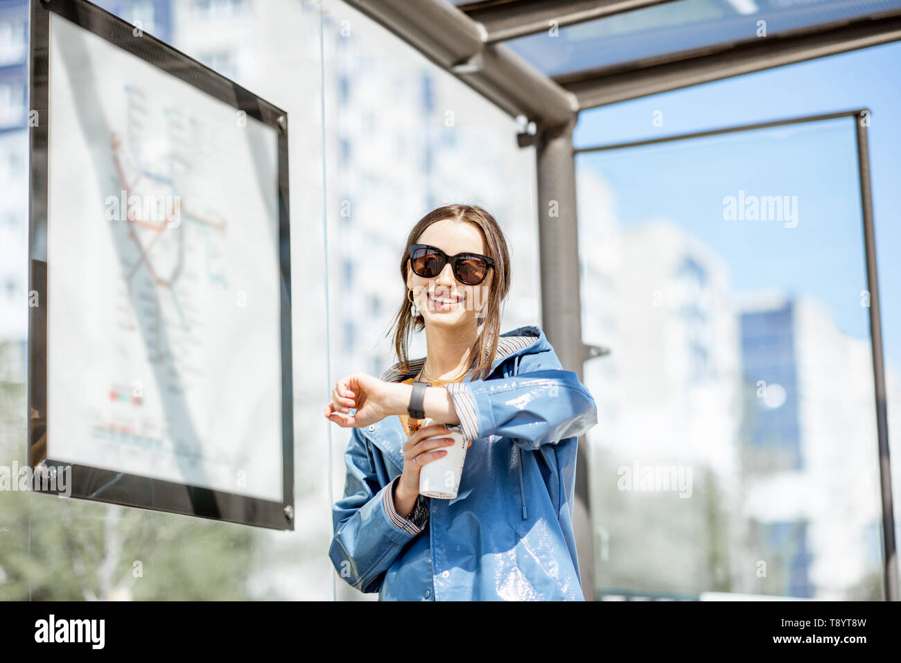 Jeune femme contrôle de temps tout en se tenant à la station de tram à l'extérieur Banque D'Images